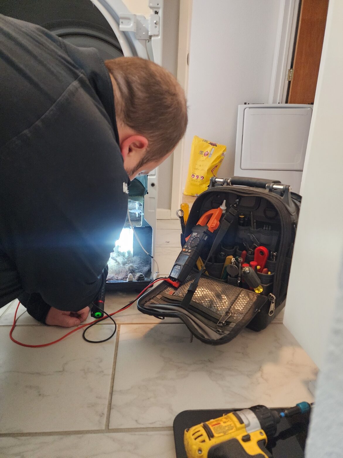 Lubbock Appliance Repair technician diagnosing a dryer with a multimeter