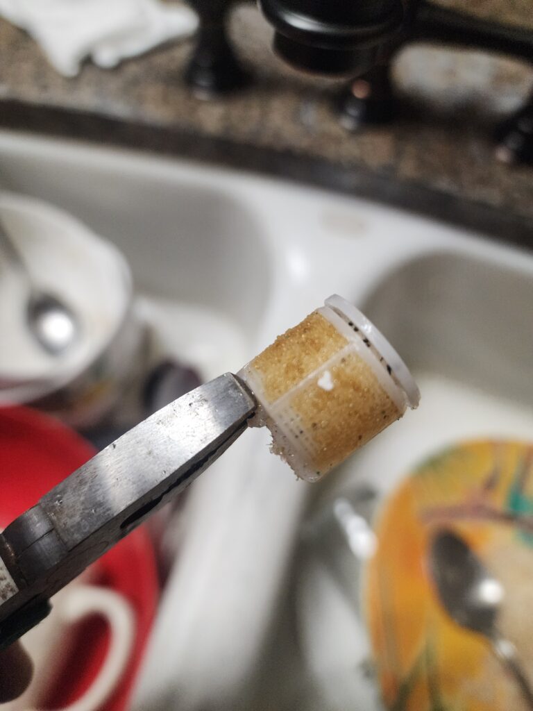 Clogged washing machine inlet screen filled with water softener resin beads