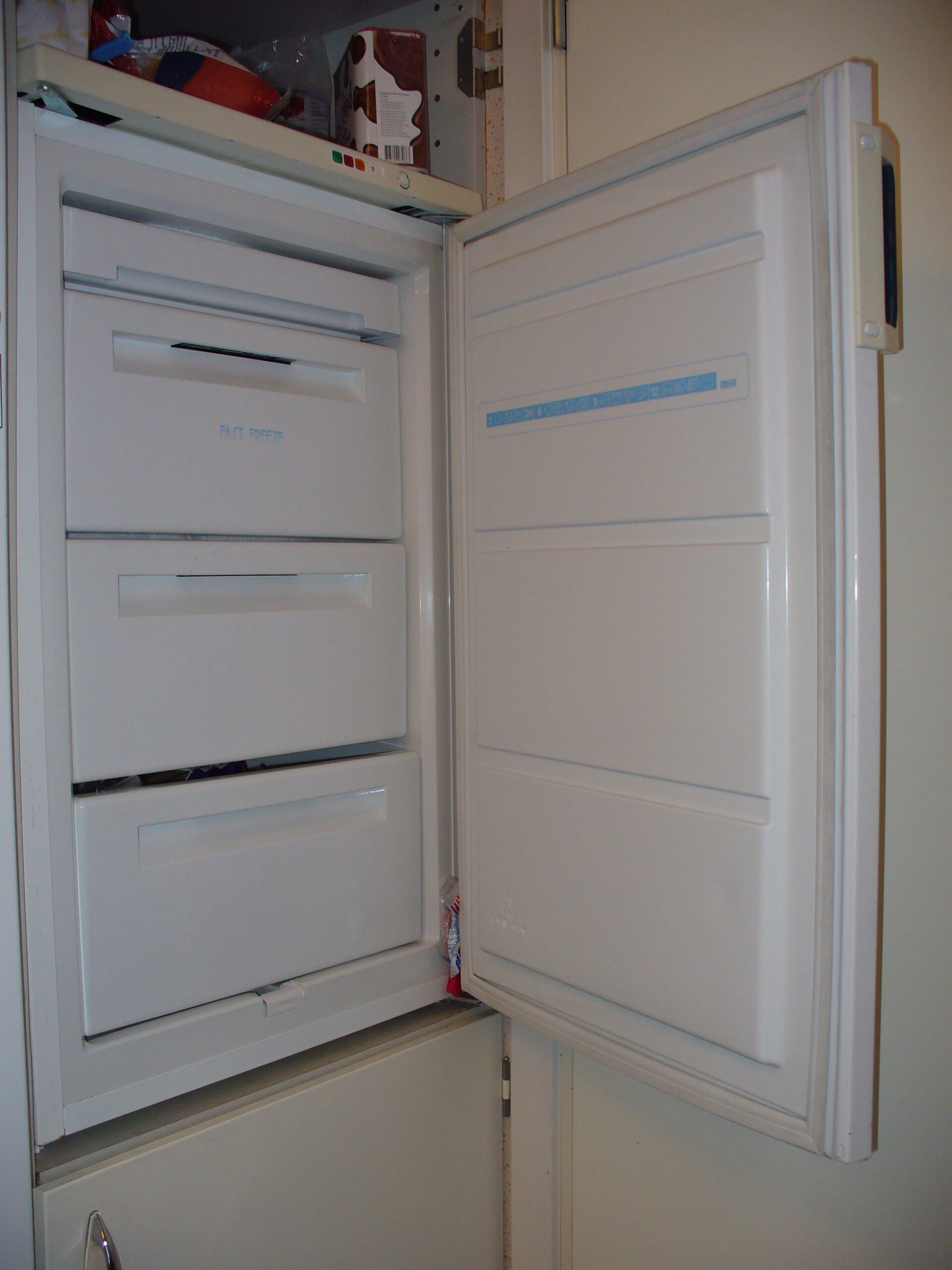 Upright freezer with door open showing where to find model and serial number tag