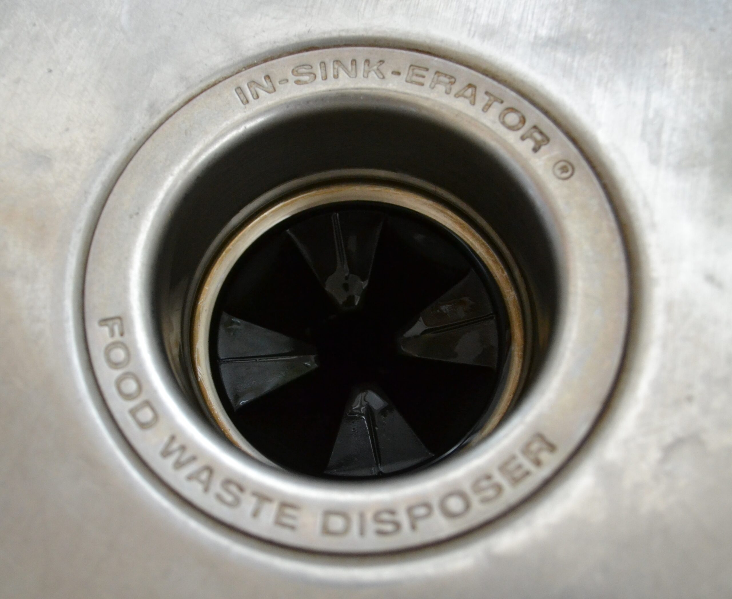 In-Sink-Erator garbage disposal viewed from above in stainless steel kitchen sink where model number is on the bottom of the unit