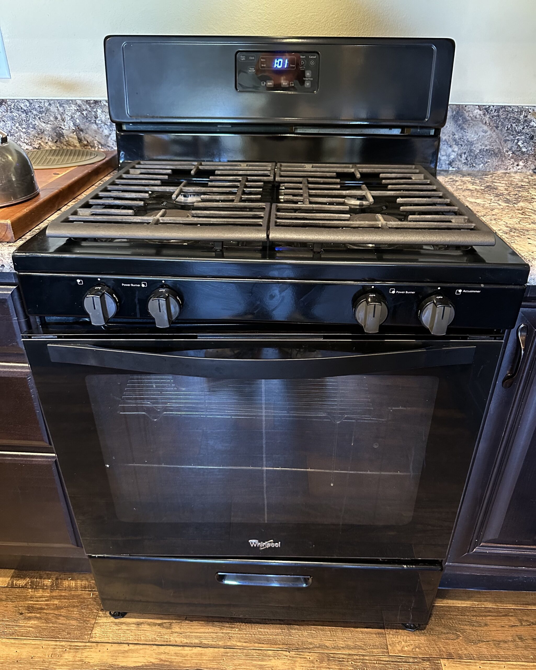 Black freestanding gas range with four burners and oven where model and serial number tag is typically behind the storage drawer